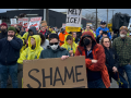 Workers gather in a March 27 protest holding signs reading "Shame" and "Melt ICE!"