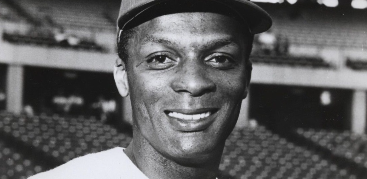 Curt Flood Center fielder Curt Flood smiles in a close-up head shot with stadium seating behind him.