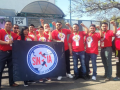 Miembros del comité de revisión salarial del SINTTIA posan con camisetas sindicales rojas y los puños en alto frente al Centro Federal de Conciliación y Registro Laboral.